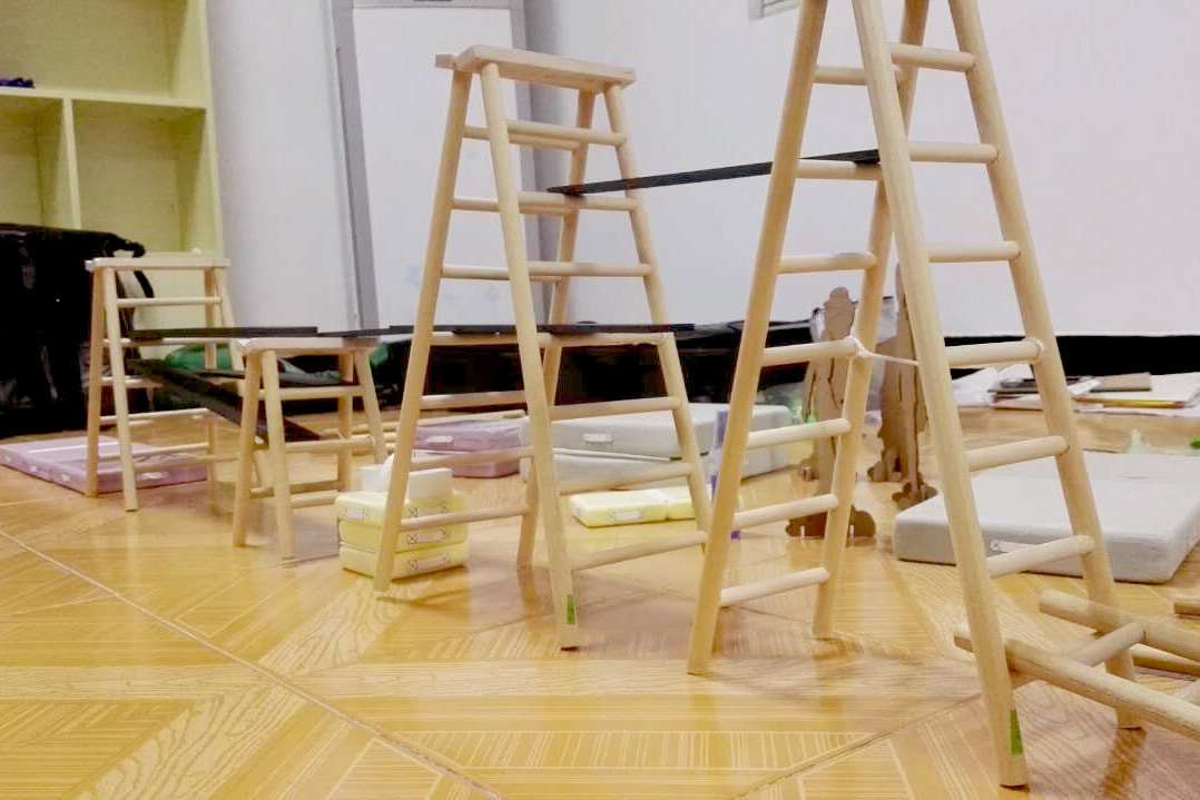 Scale models of folding wooden ladders and wrestling mats in different sizes. They are arranged in a line, suggesting an obstacle course.